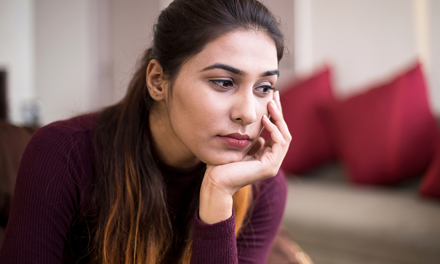 A woman with long hair rests her chin on her hand, appearing deep in thought.