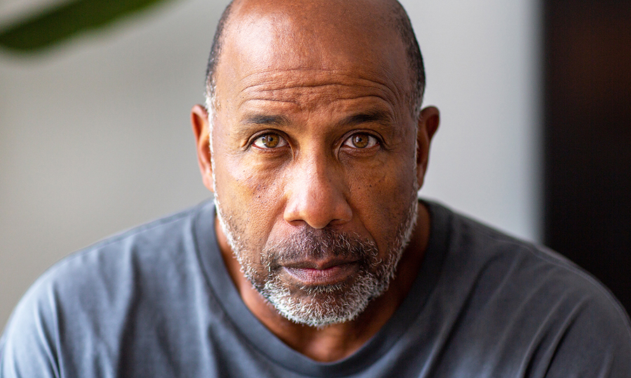 A middle-aged man with a bald head and salt-and-pepper beard gazes intently at the camera.