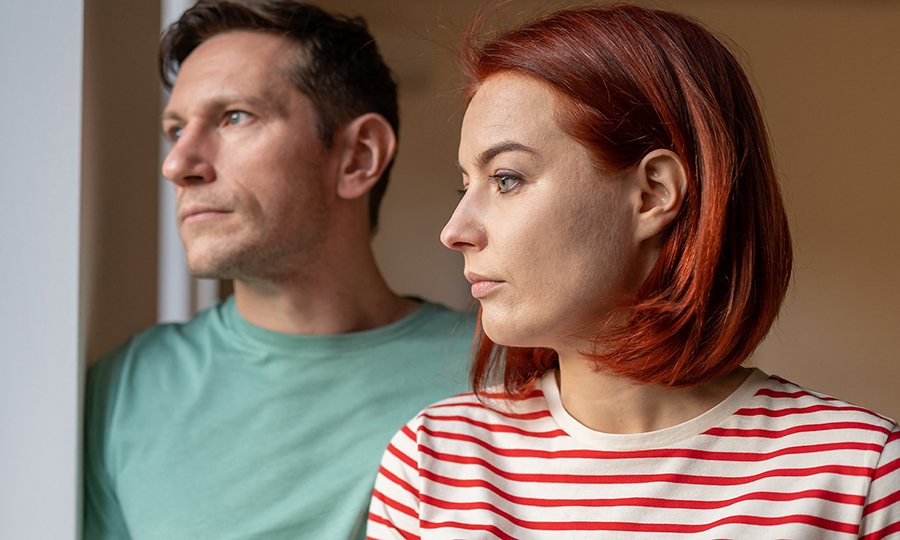 A man and woman gaze thoughtfully out of a window.