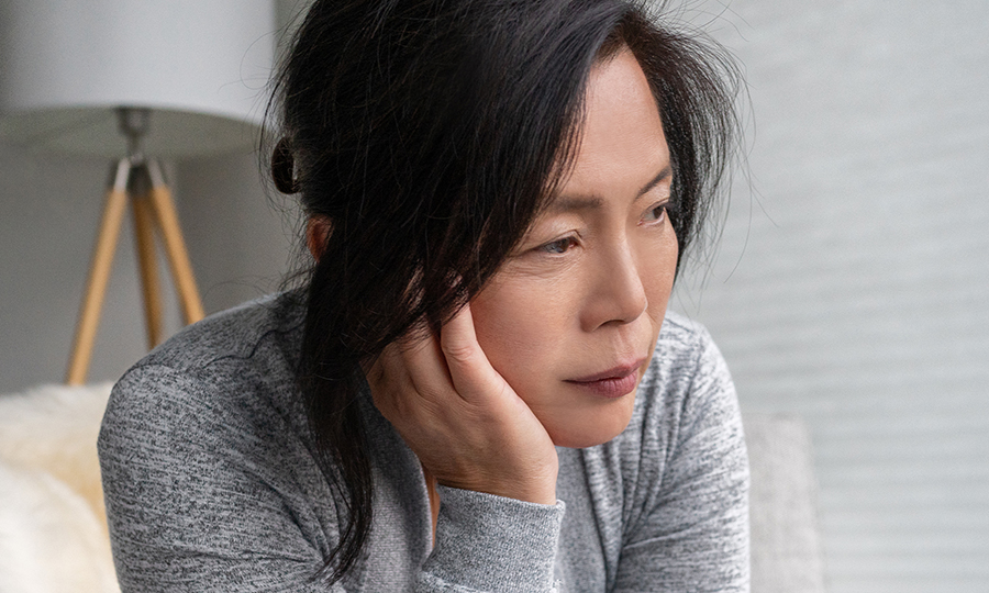 A woman with long dark hair looks thoughtful and introspective.