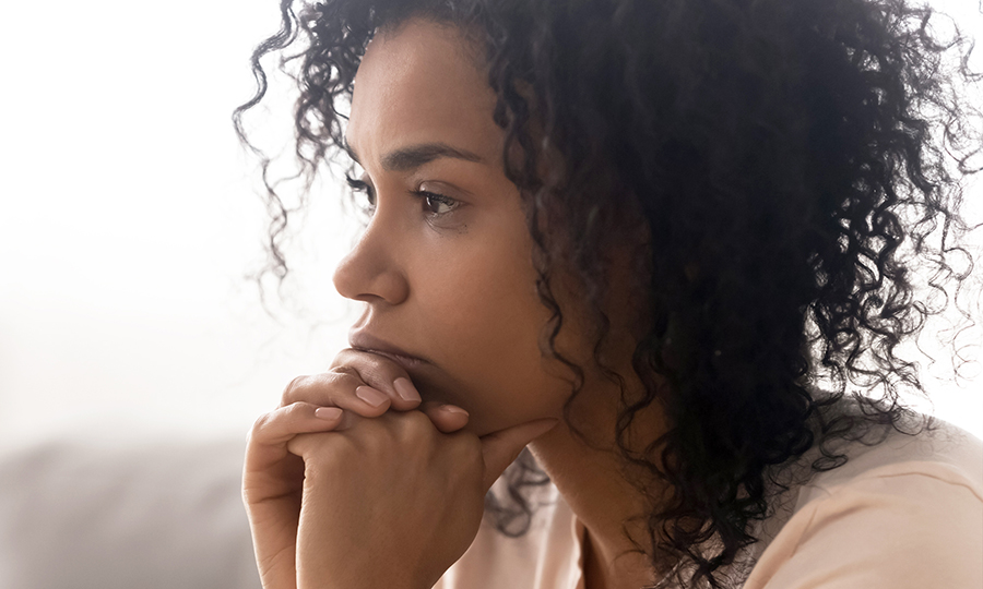 A woman with curly hair looking pensive and worried.