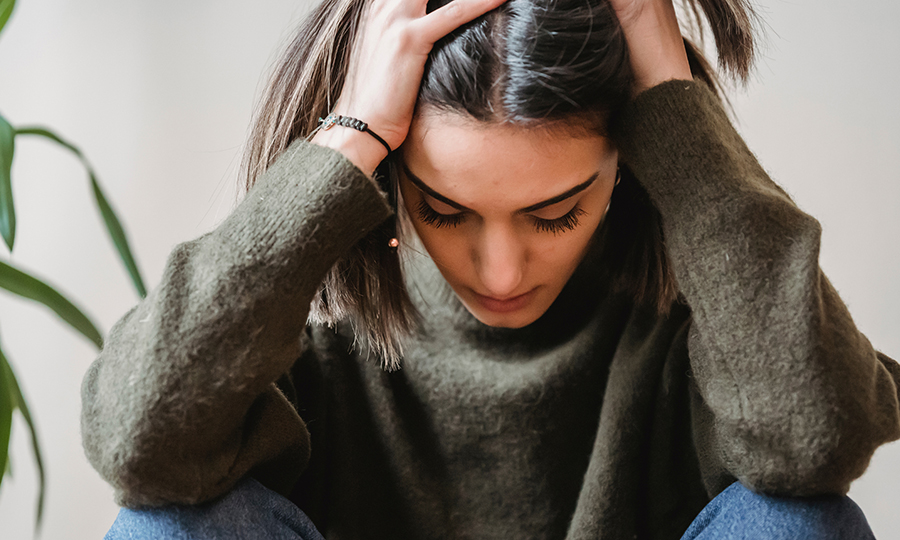 A young person sits with their head in hands, conveying stress or contemplation.