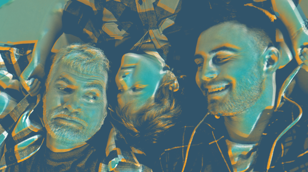 Three different generations of men lying on the floor and smiling.